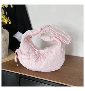 Detail of pink heart-quilted crescent shoulder bag with adjustable fabric strap