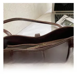 Detail shot of the dark brown leather bucket bag showing smooth texture and golden zipper