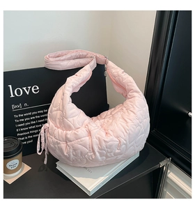 Detail of pink quilted heart texture on a crescent shoulder bag with coin pouch accessory