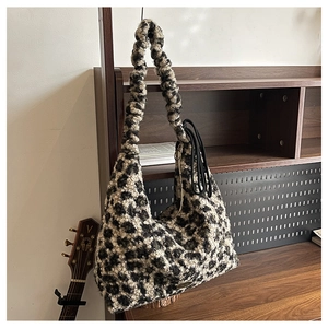 Detail of plush leopard print faux fur shoulder bag with warm texture on wood stand