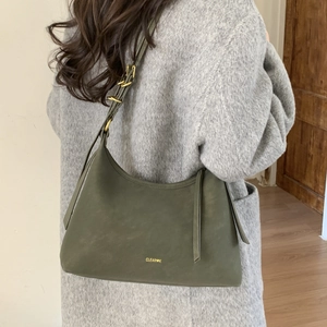 Detail of adjustable strap with gold metal rings on an olive green leather shoulder bag