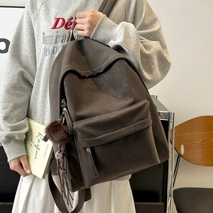 Close-up of vintage coffee brown faux leather backpack with fuzzy ball and bead charms