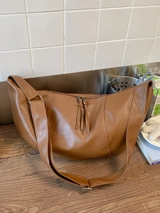 Brown faux leather dumpling shoulder bag with pebble texture and adjustable strap