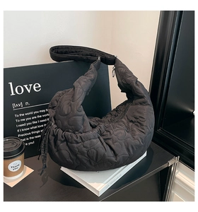 Detail of black quilted shoulder bag with 3D heart pattern and metallic zipper closure