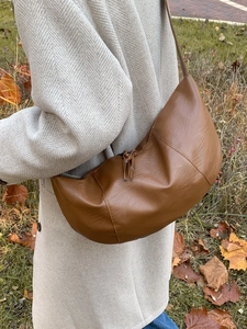 Minimalist brown leather half-moon crossbody bag with tassel and autumn street style