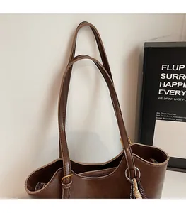 Detail of dark brown leather tote bag showing long shoulder straps and silver ring hardware
