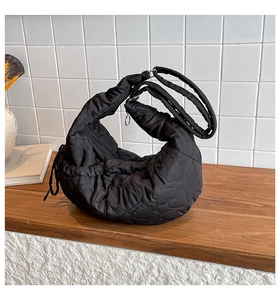 Detail of black heart-quilted tote bag on wooden table with elegant home decor