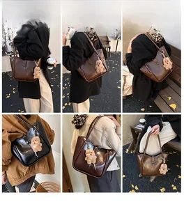Detail view of stylish vintage bucket bag with plush bear charm in dark brown and black