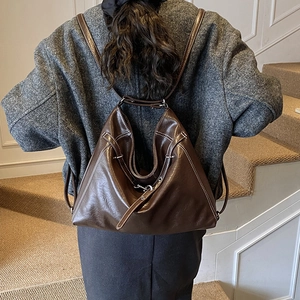Detail der dunkelbraunen Leder-Tote mit Kontrastnaht auf der Schulter einer eleganten Frau