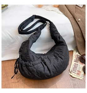Detailed scene of a black heart-quilted crescent bag on wooden floor with vintage props