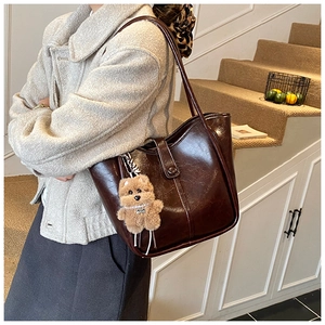 Side view of dark brown retro bucket bag with glossy finish and cute puppy pendant