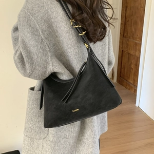 Detail of black suede shoulder bag with gold metal buckles and branded lettering
