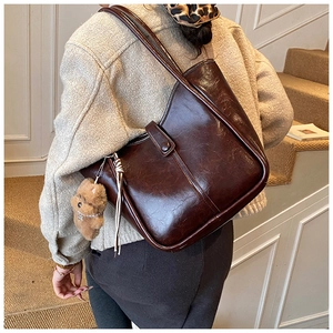 Deep brown oil-wax leather tote bag with a cute plush bear pendant shown on model