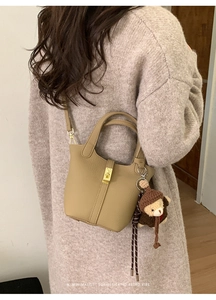 Litchi texture leather bucket bag with a cute bear charm shown on a casual model outfit