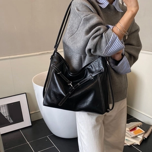Detail der schwarzen Shopper-Tasche mit weißen Kontrastnähten und Zierriemen