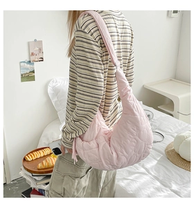 Detailed close-up of pink heart-quilted crescent bag worn on shoulder in cozy room