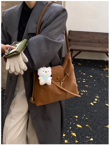 Detailed macro shot of vintage brown leather tote bag with a cute white plush bear pendant
