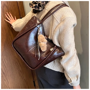 Detail of dark brown oil wax leather tote bag with a khaki faux fur pompom charm