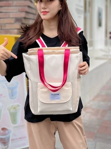 Sac à dos étudiant beige avec sangles rouges et compartiment PC dans une scène de rue