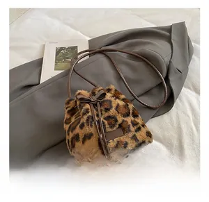 Detailed close-up of leopard print plush bucket bag with leather drawstring and bow detail