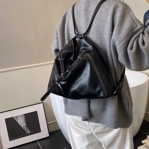 Details einer schwarzen Leder-Tragetasche mit weißen Kontrastnähten und geometrischer Form