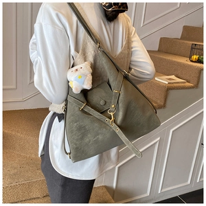 Olive green tote bag with bear charm and adjustable strap shown on model in interior