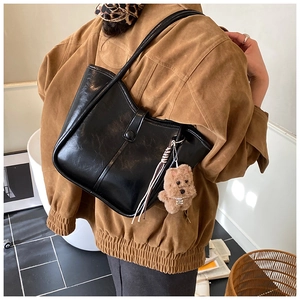 Detail of black large bucket bag with fringe tassel and cute plush puppy charm