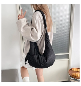 On-body shot of a black heart-quilted shoulder bag with padded soft texture and large capacity
