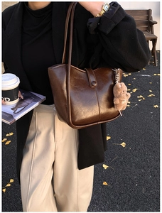 Detail of dark brown vintage PU leather bucket bag with a cute plush bear charm