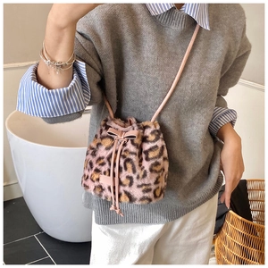 Detail showing plush leopard print texture and pink leather bow on crossbody bucket bag