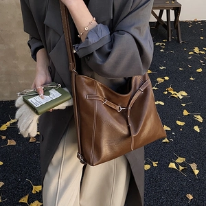 Detail einer großen braunen Hobo-Tasche mit weißen Ziernähten und Metallschnallen-Verzierung