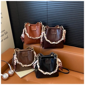 Detailed close-up of four stylish bucket bags in brown, coffee, and black with chain straps