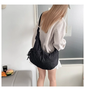 Detail of heart-quilted black nylon shoulder bag with decorative side drawstring accents