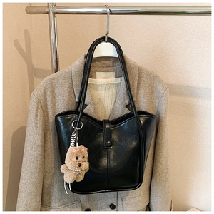 Detail of black large-capacity PU leather tote bag with a cute plush puppy pendant