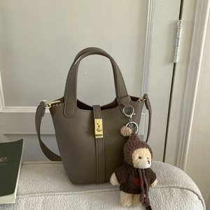 Detail of taupe litchi grain leather bucket bag with gold lock and cute bear charm