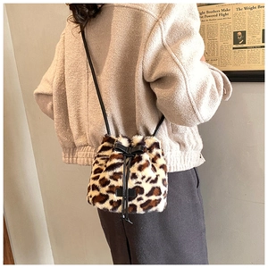 Detail of plush leopard print bucket bag with drawstring closure worn by a model