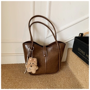 Detail of dark brown retro PU leather underarm bag with cute plush puppy charm