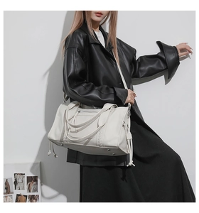 Close-up of white leather tote bag with drawstring detail and protective metal feet studs