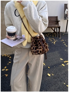 Detail of plush leopard print bucket bag with brown leather drawstring and bow