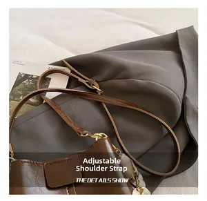 Detail showing the adjustable leather shoulder strap and gold hardware of the brown bucket bag