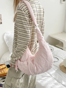 Pink heart quilted shoulder bag worn by model in a cozy indoor home setting