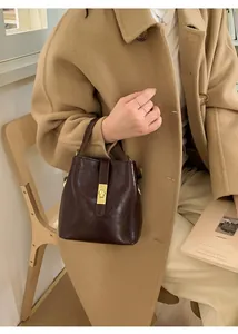 Detail of dark brown oil wax leather bucket bag with elegant golden vertical lock