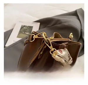 Detail of dark brown bucket bag featuring gold metal hooks and a decorative floral silk scarf