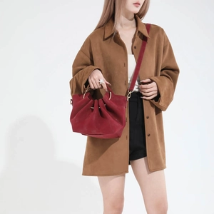 Sac seau rouge foncé à plis et anse dorée porté par un mannequin en studio