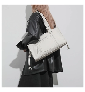 Macro shot of cream tote bag with woven textures, front zipper pocket and metal rivets