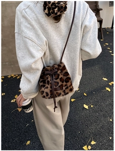 Outdoor street style view of plush leopard print bucket bag with autumn leaves