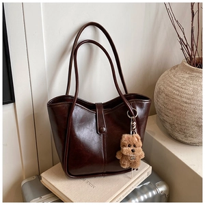 Detail of dark brown tote bag with magnetic closure and cute bear plush charm accessory