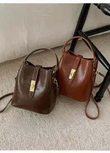 Detail of vintage bucket bag featuring glossy leather texture and gold twist-lock closure
