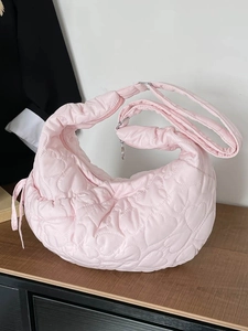 Pink heart quilted puffer shoulder bag with adjustable strap on wooden surface