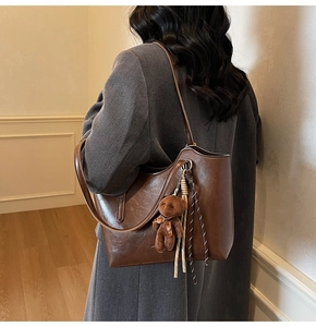 Detailed texture of brown retro tote bag with a cute plush bear pendant and ribbon